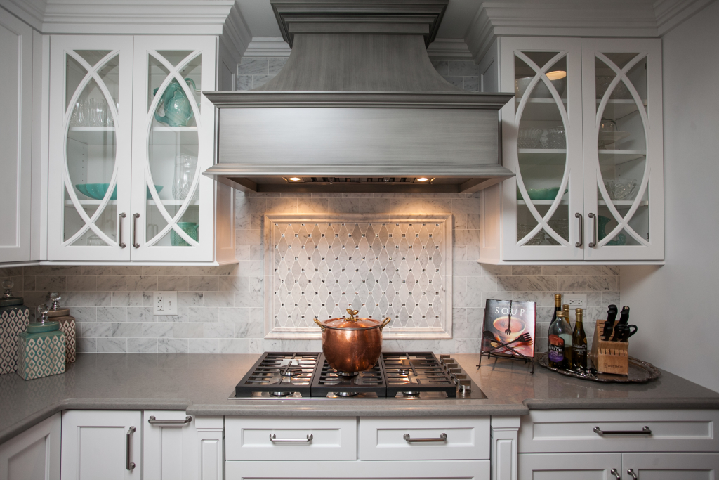 What a beautiful focal point in this kitchen. A custom wooden hood with artistic finish, and custom mullioned glass doors. 