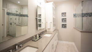Elongated white double vanity with tower cabinet linen storage.